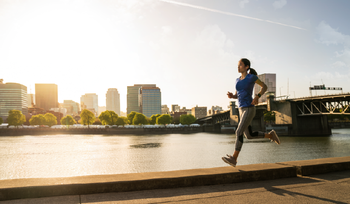 Woman running in front of cityscape at sunrise