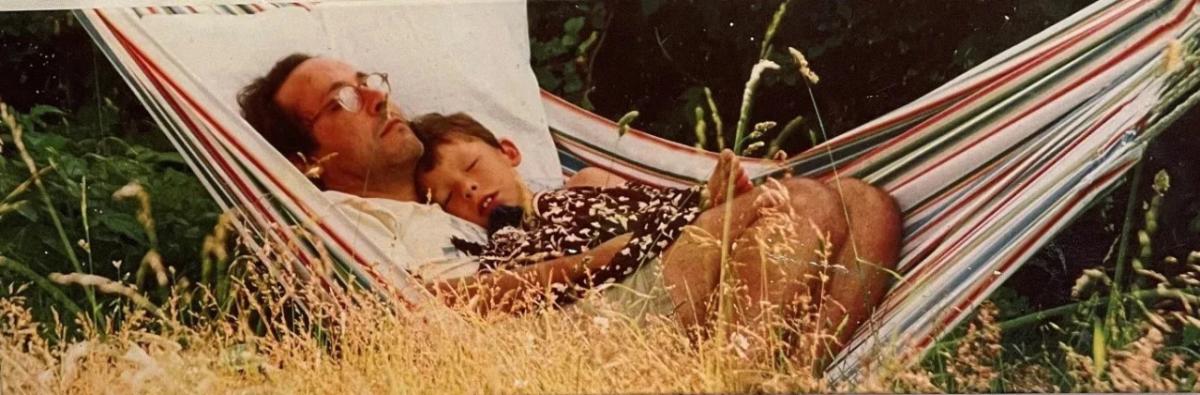 father and child sleeping in a hammock