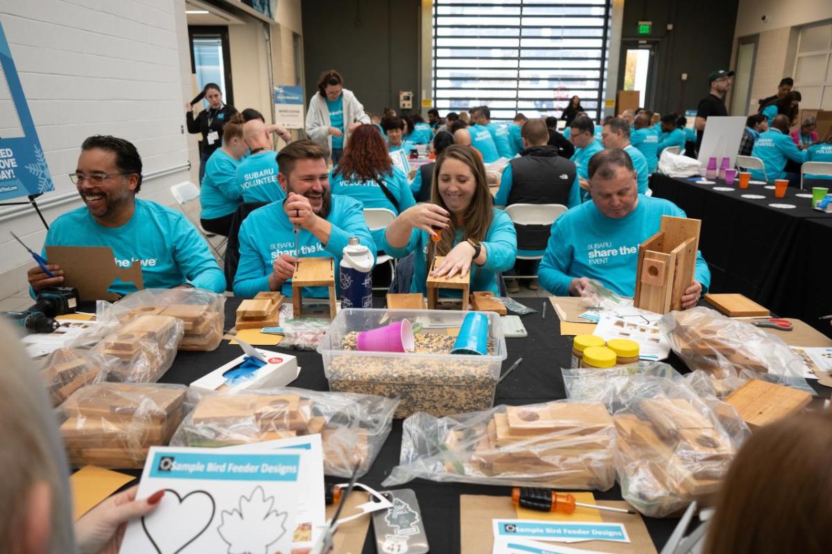 People in turquoise shirts making birdhouses