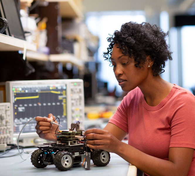 a person working on a rc vehicle, electrical equipment to their side