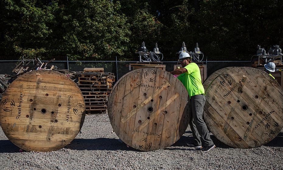 Worker rolling a wooden spool