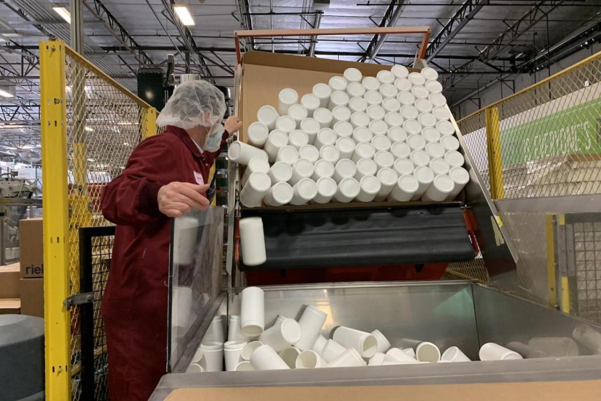 canisters being dumped into a large container in factory