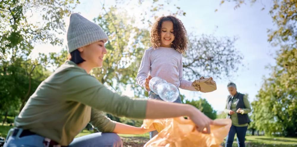 Two adults and a child collecting trash in a park setting.