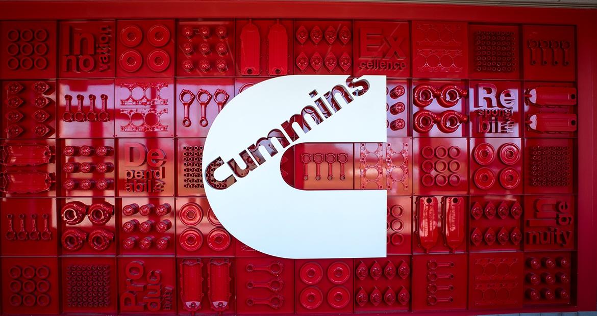 Cummins logo over a red patterned wall.