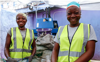 Two people in high-vis vests and hair protection smile at the camera.