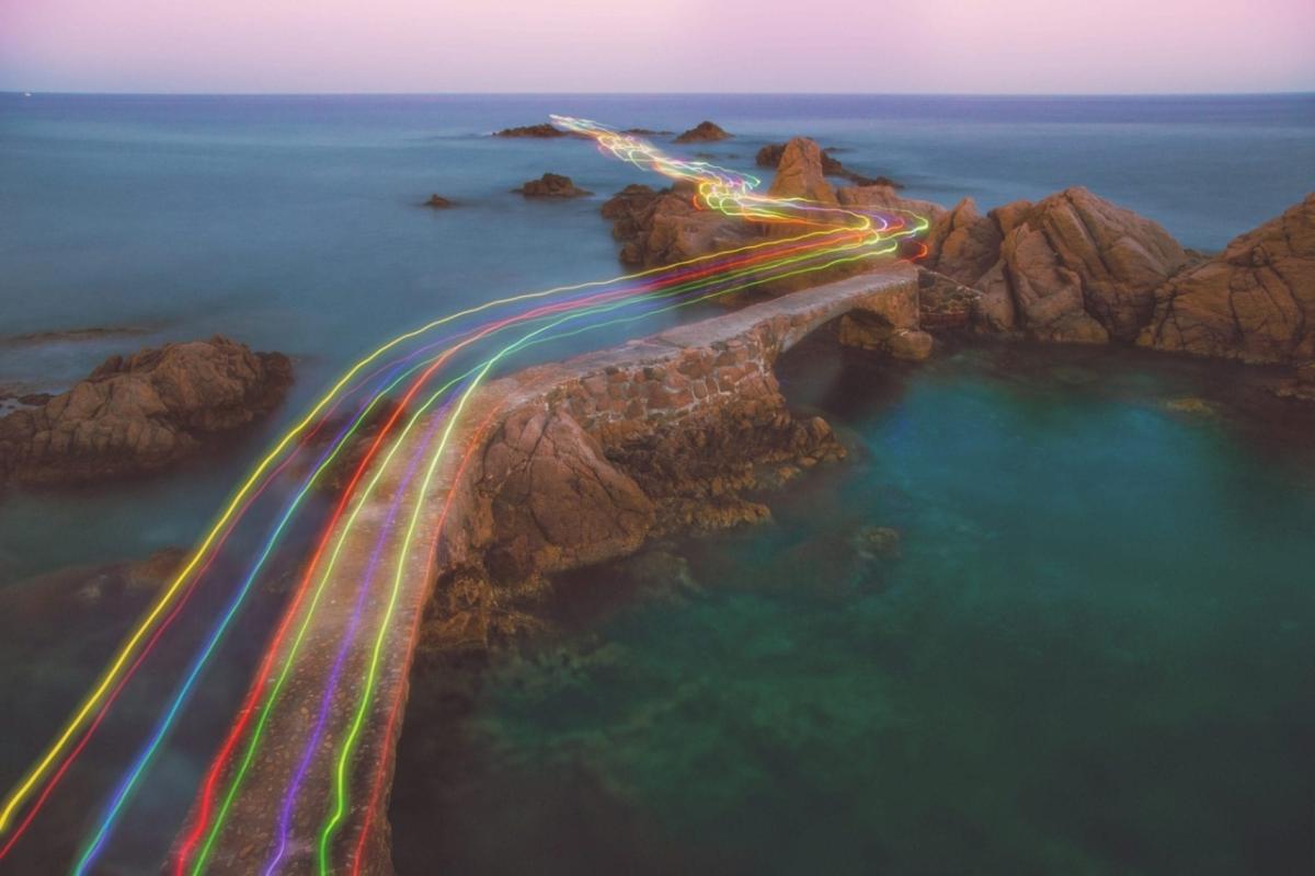 streams of colored light over a rocky coastline