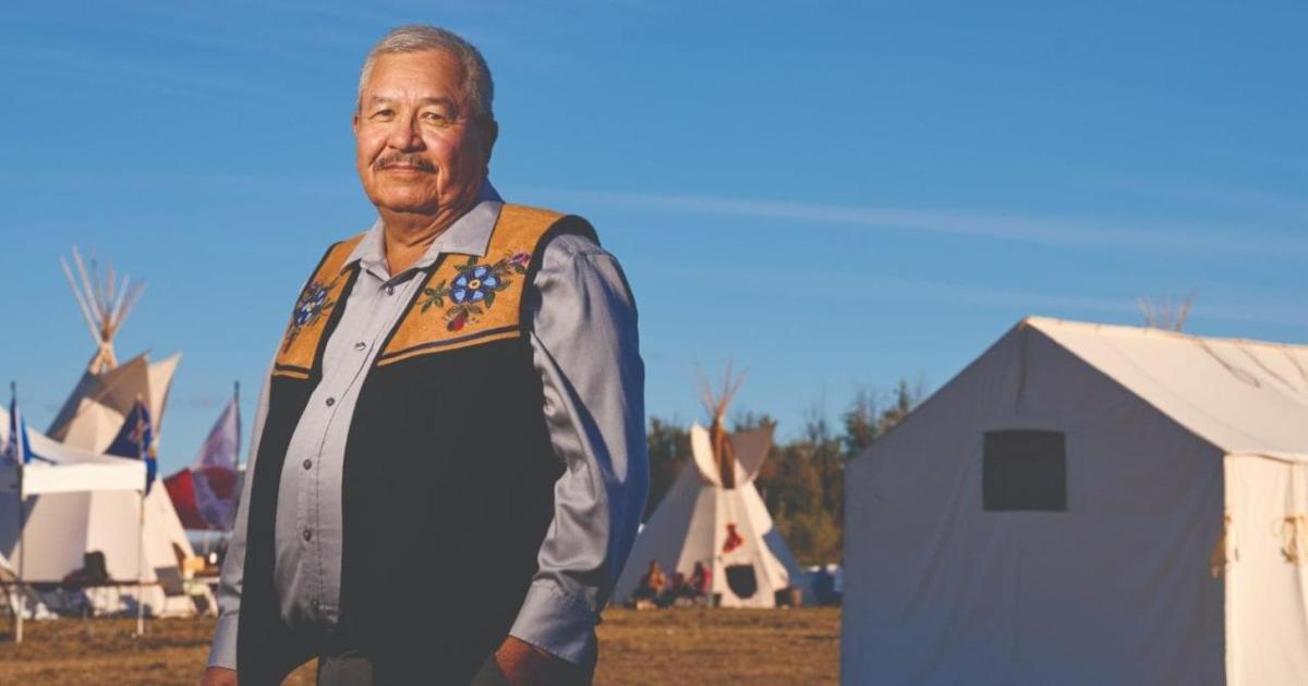 Ron Javier, indigenous buildings in the background.