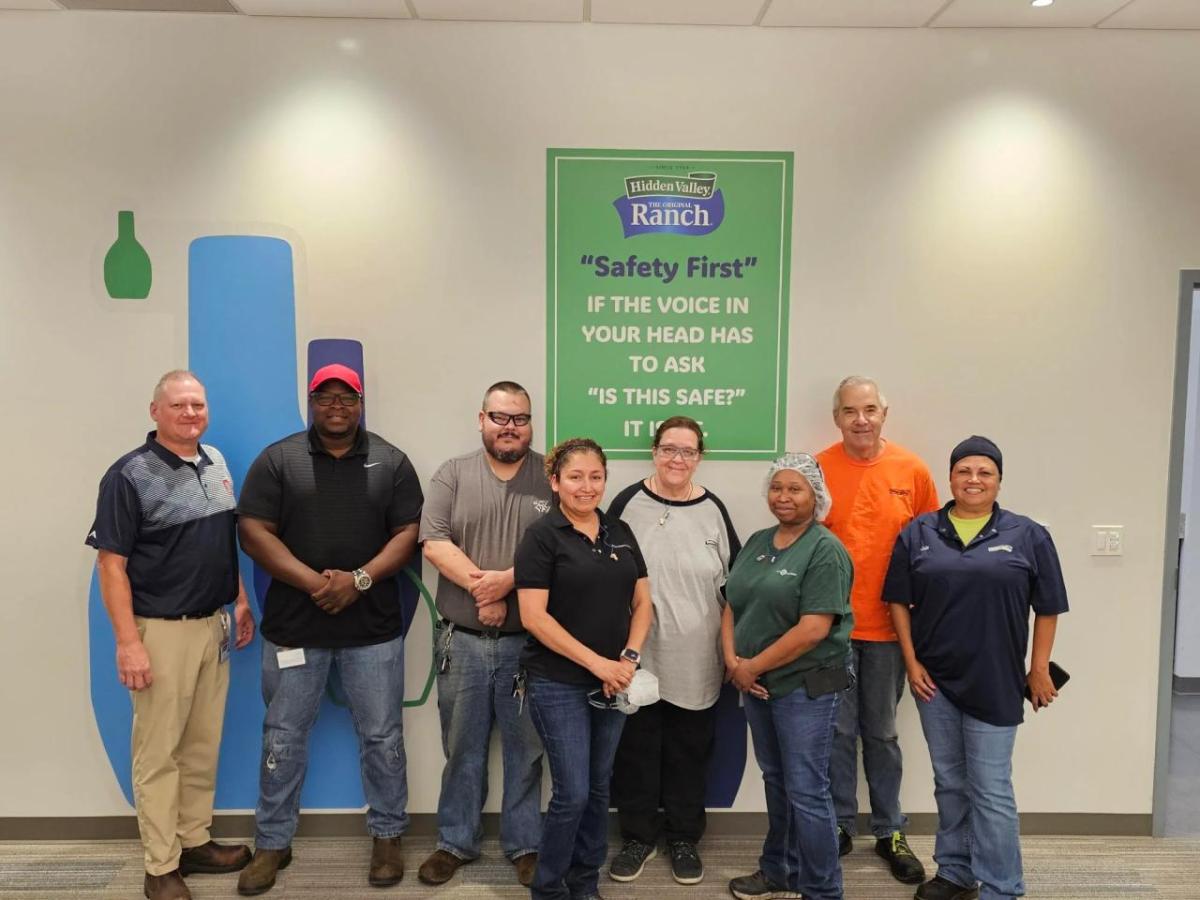 A team posed by a sign "Safety First"