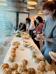 a line of people wearing protective masks making sandwiches