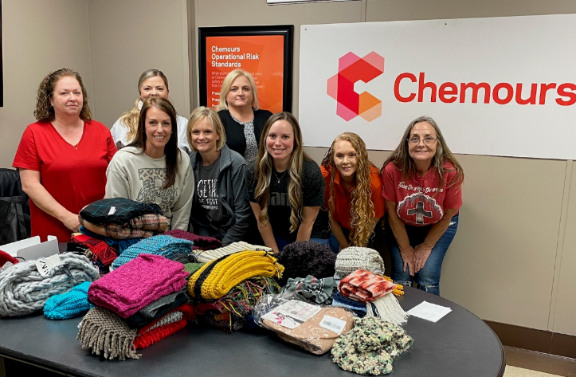 A group of volunteers behind a table full of handmade scarves.