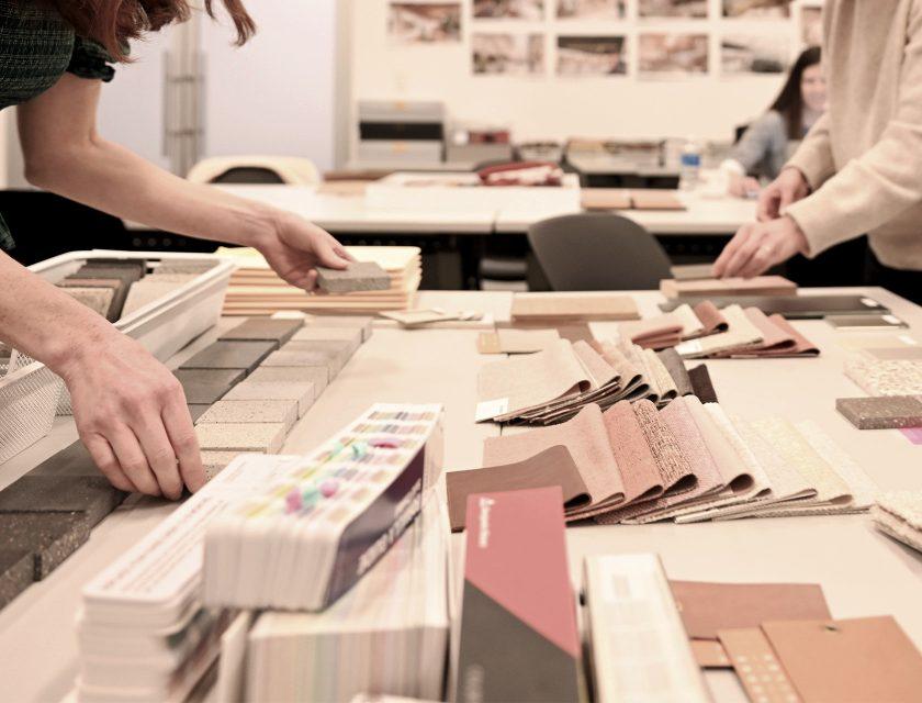 people selecting swatches from a table full of different texture, color, material samples.