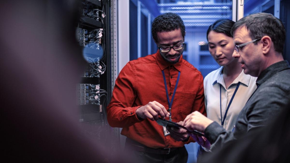 Three people working in a server room