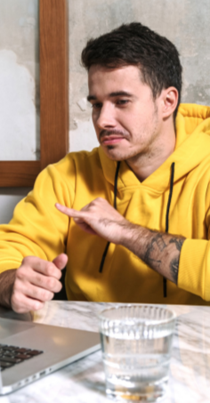 a person using a hand sign to a laptop screen