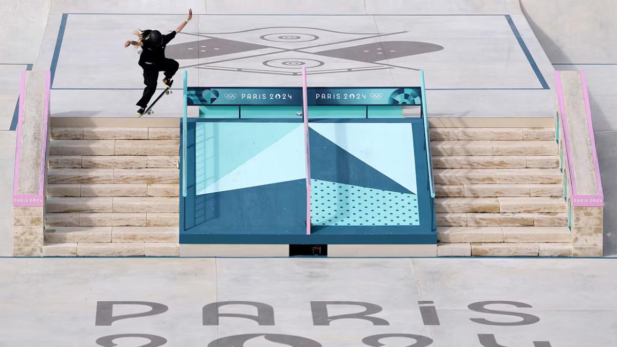 A person skateboarding over stairs "Paris 2024" on the cement at the bottom of the staircase.