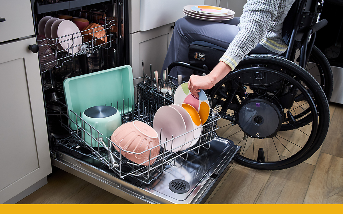 A person in a wheelchair unloading a dishwasher