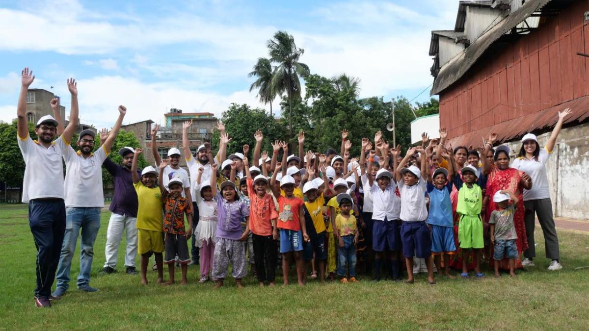 A group of youth and adults posed outside with arms up.