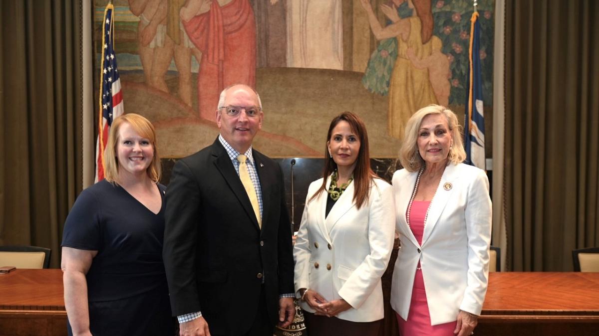 Four people in a government building, posed for the camera.