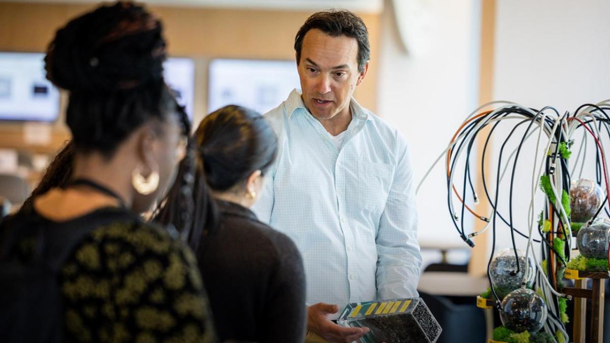 A person talking to others, holding an electronic device