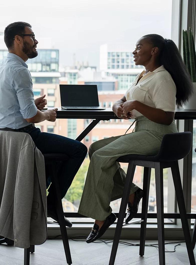 two people sitting at a table with a computer