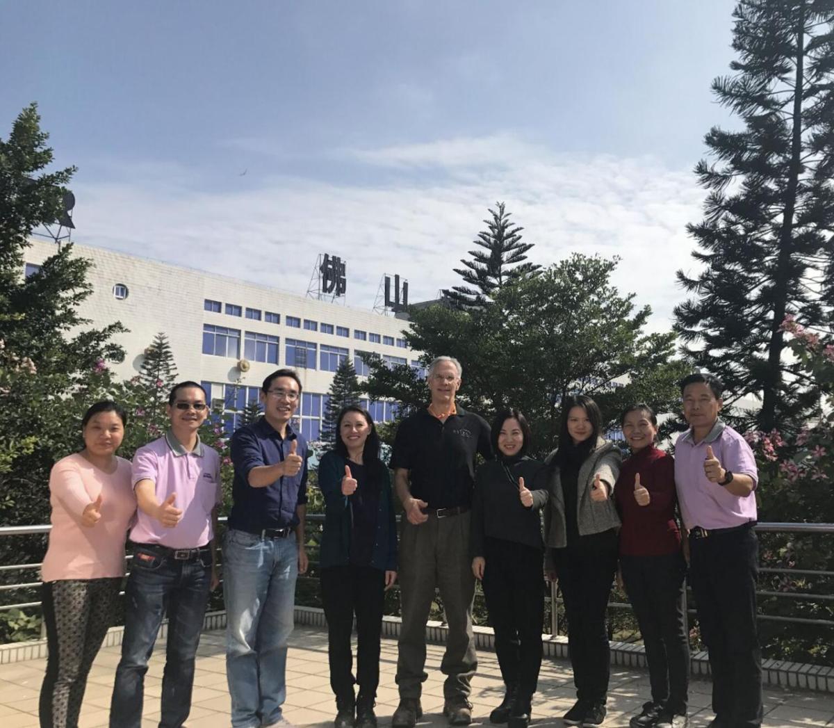 A group of people posed outside giving 'thumbs-up'.