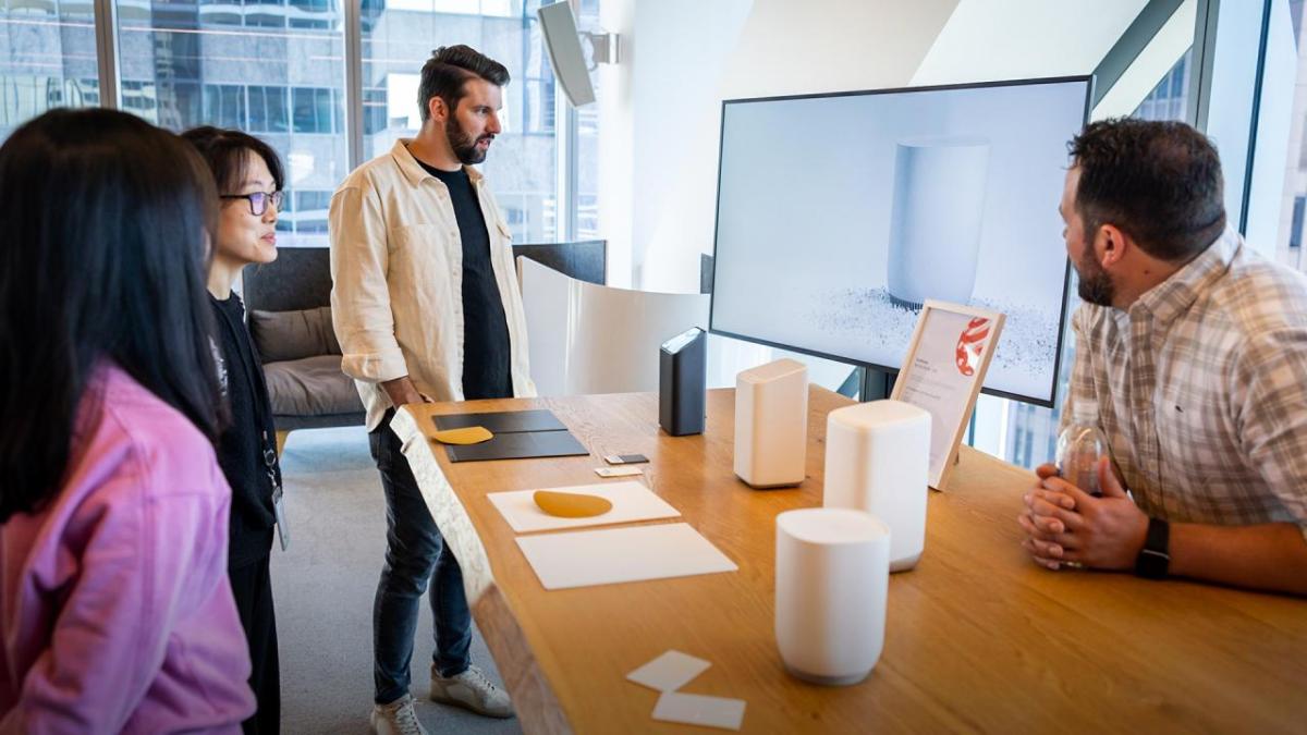 A person behind a table displaying different products as others look on.