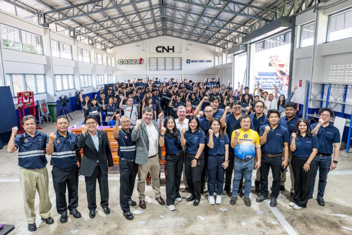 A large team posed in an open covered building, most with one fist half-raised. 