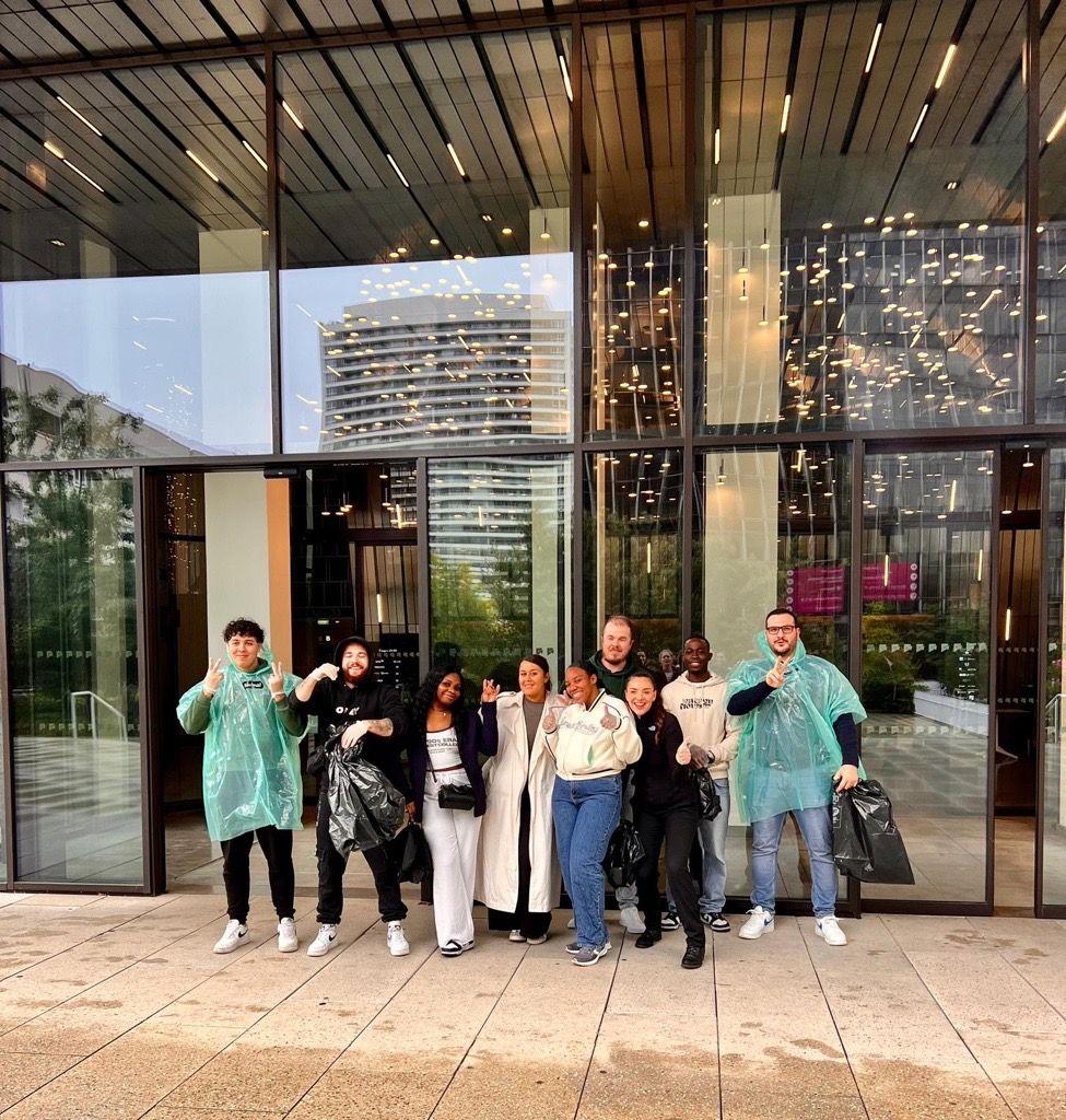 A group posed outside a building. Some giving thumbs-up.