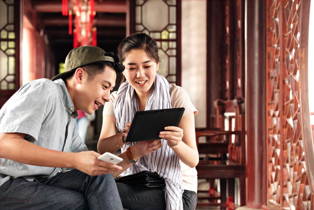 Two people looking at a handheld device indoors.