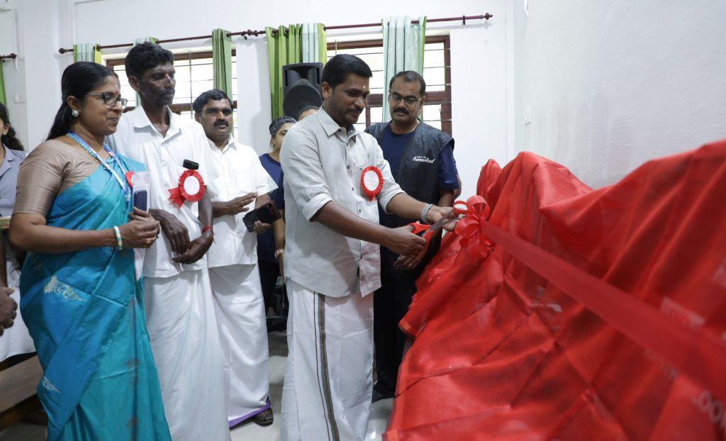 People standing and watching another cut a long red ribbon.