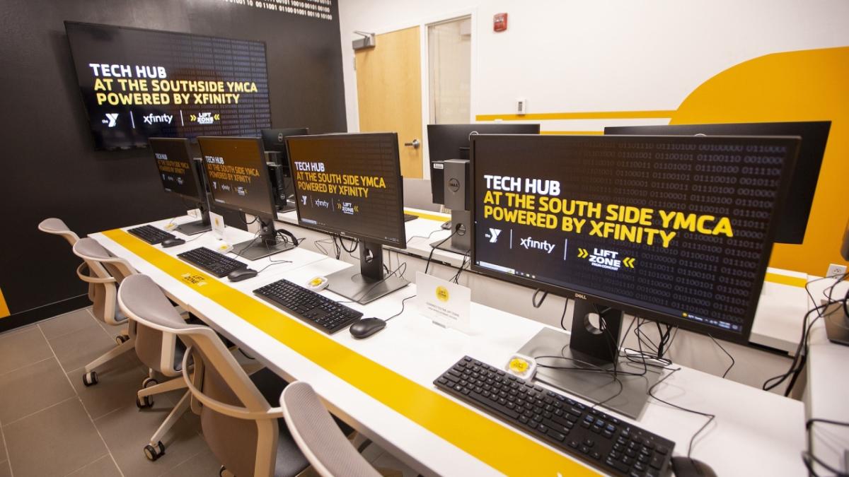 two rows of desktop computers, chairs in a room "Tech Hub" on all the monitors