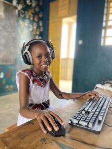 A smiling child with headphones using a computer.