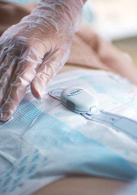 a gloved hand touching an incontinence underwear with an attached monitor