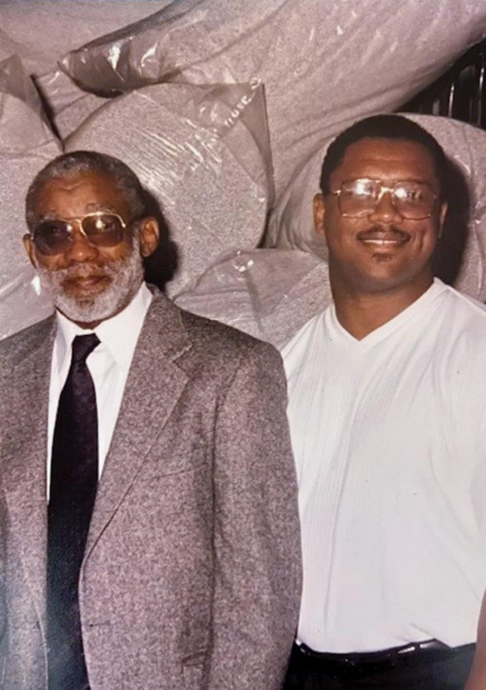 Pevas Bailey and another standing in front of bags of materials.