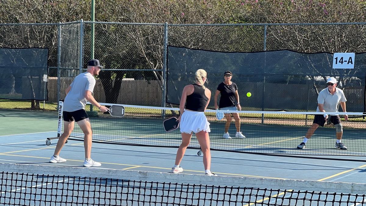 Four people playing pickleball