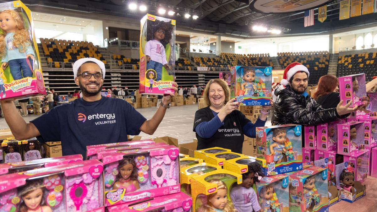 Volunteers holding up toys from a table full.