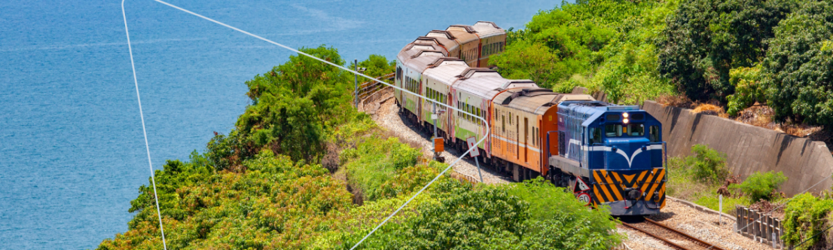 A train going down a track. A coastal scene.