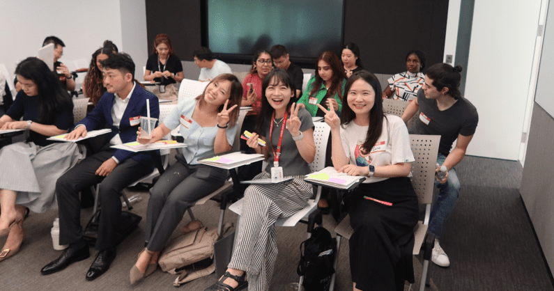 Students in chairs, some smiling and giving a peace sign to the camera.