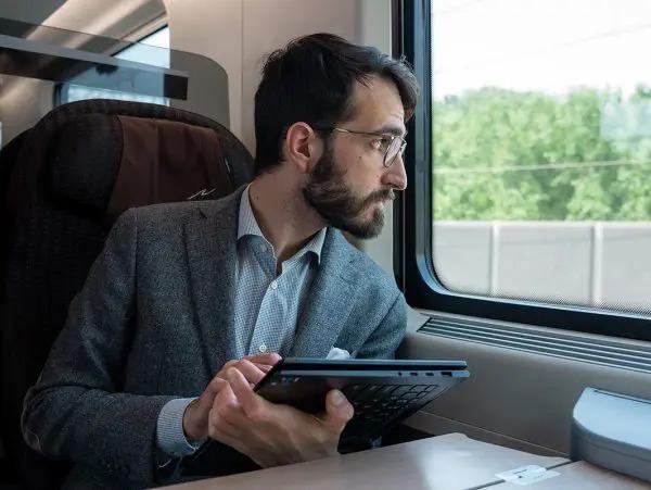 Ruggero Rollini looking out a train window, holding an open tablet.