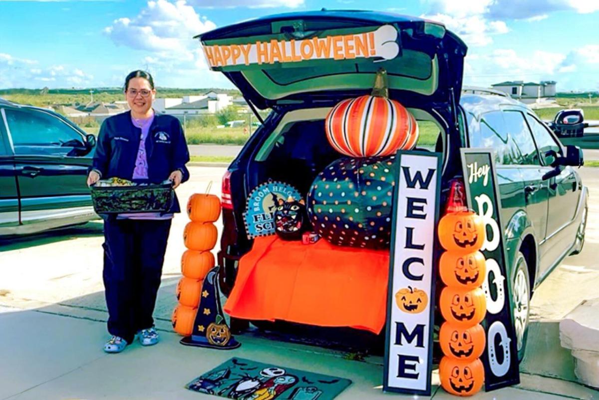 Angelica next to an open car trunk decorated for halloween.