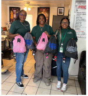 Three smiling people posed holding up small backpack/bags.