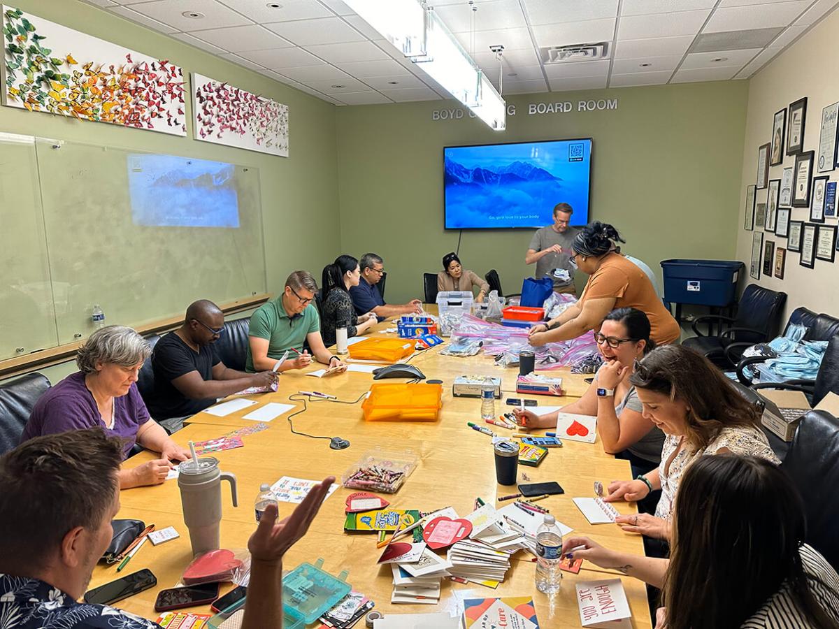 A group seated at a large conference table doing crafts.