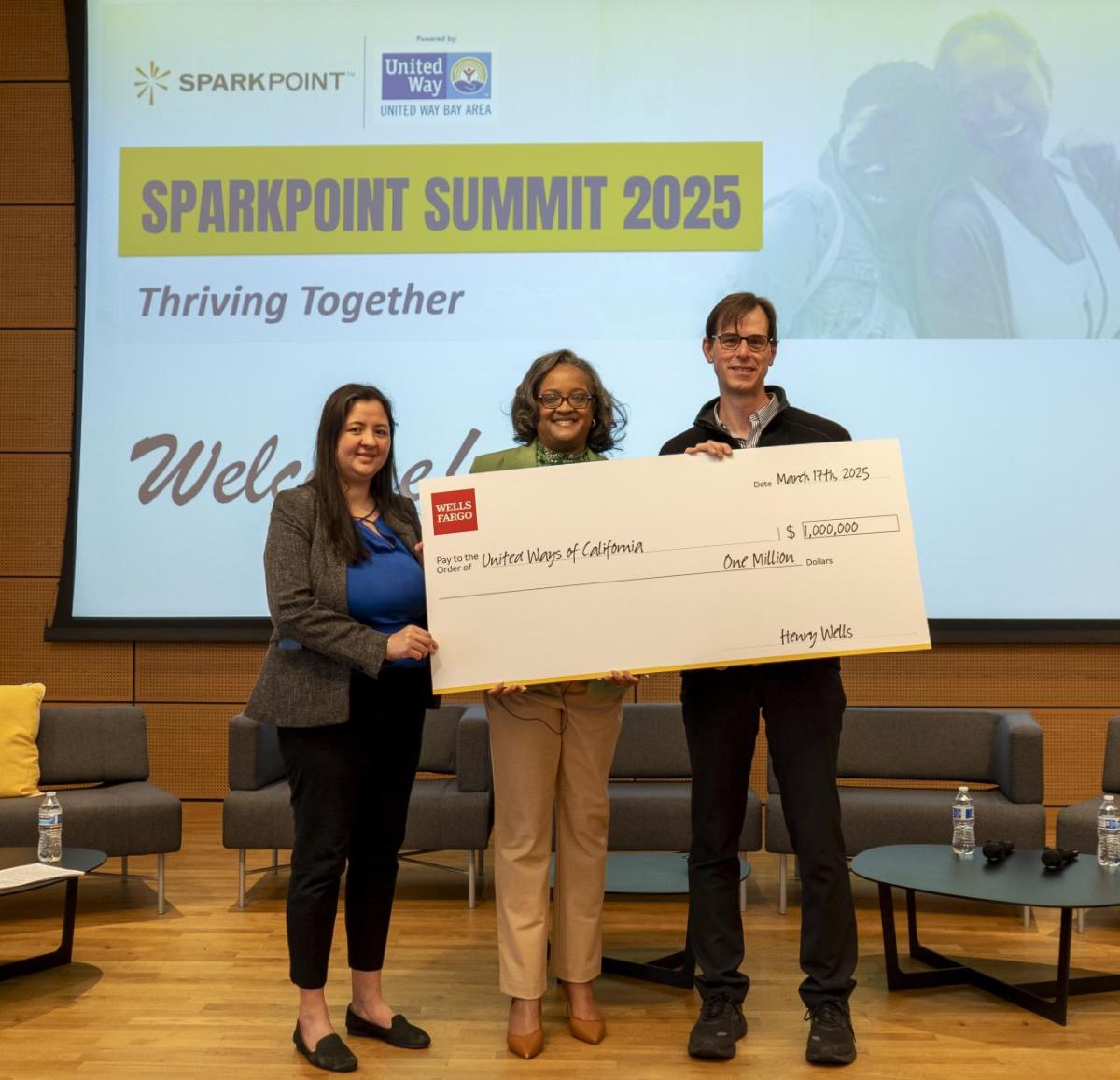 Three people, two women and one man, holding a big check