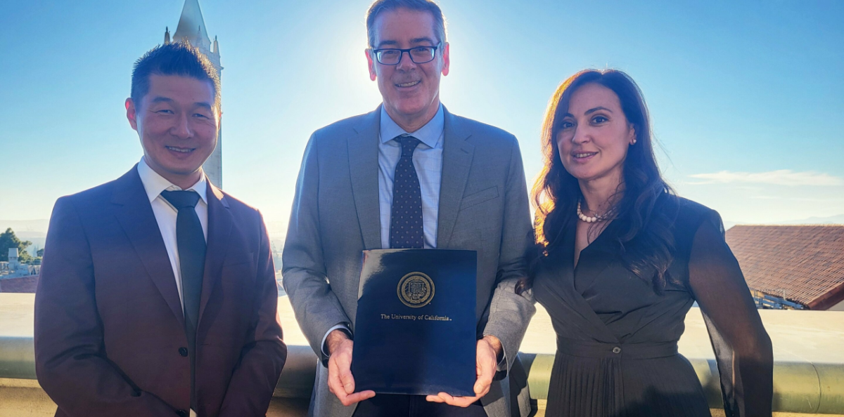 Three people standing together, holding a report