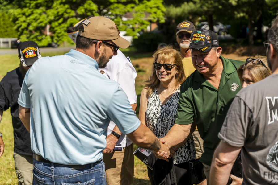 Sgt. David Long shaking hands of others, including veterans