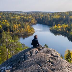 Person sitting on rock, looking over lake