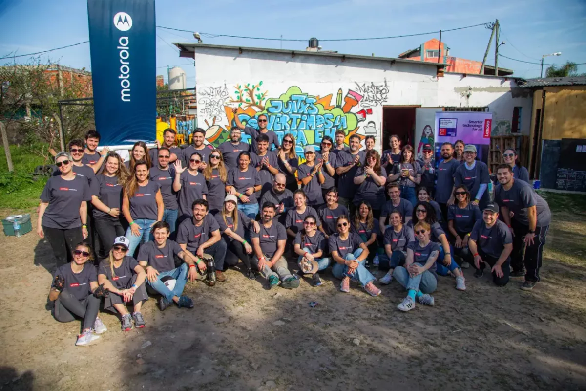 A group of volunteers posed outside a small building. Motorola sign to the side.