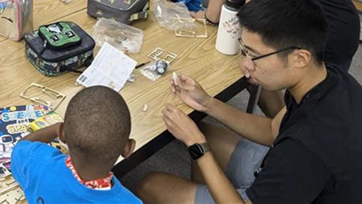 An adult helping a child with a project at a table.