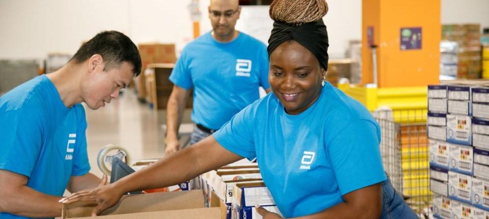 Volunteers in a warehouse setting packing boxes.