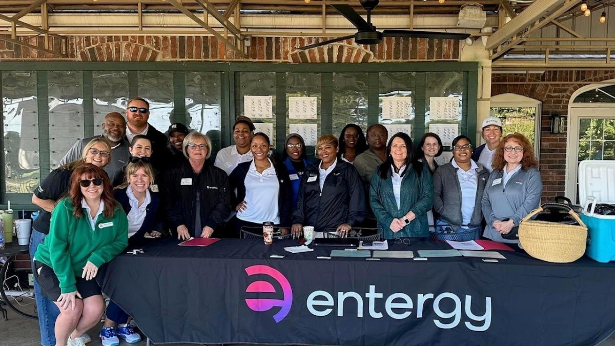 A group posed behind a table with "entergy" sign in front.