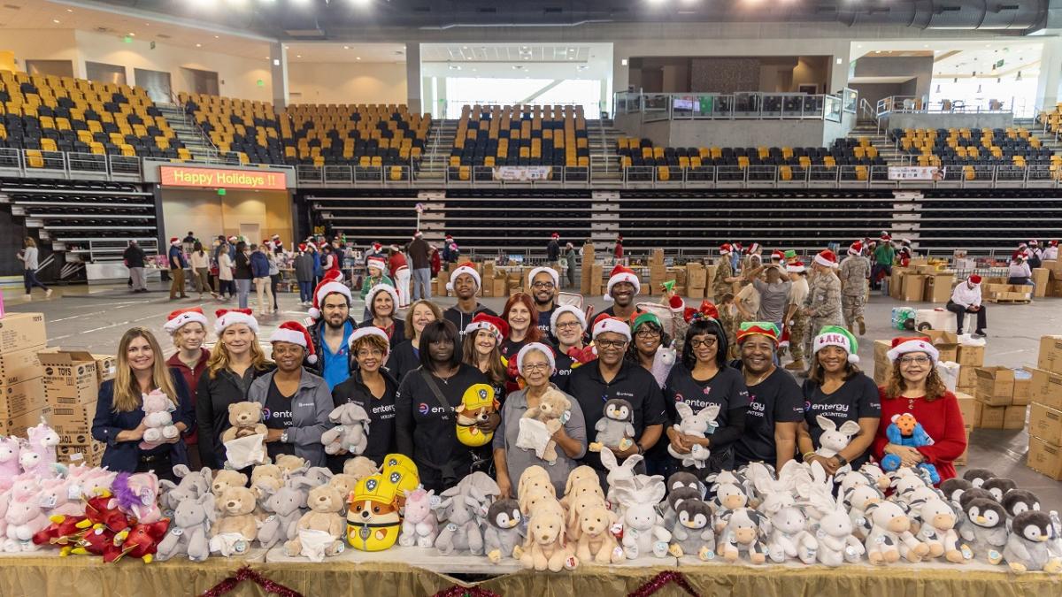 Volunteers posed behind tables of toys in a gymnasium